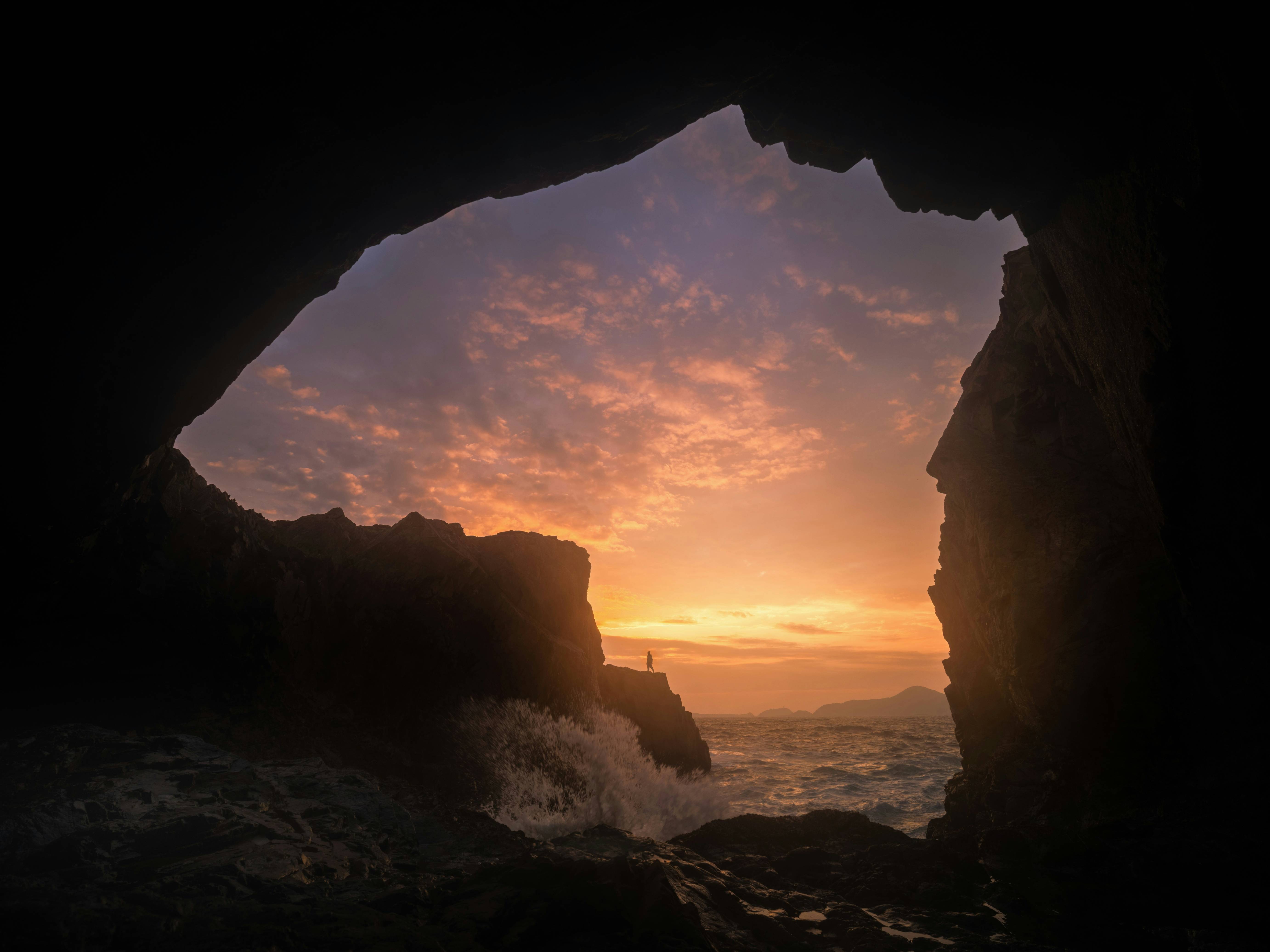 The sun is setting over the ocean from inside a cave