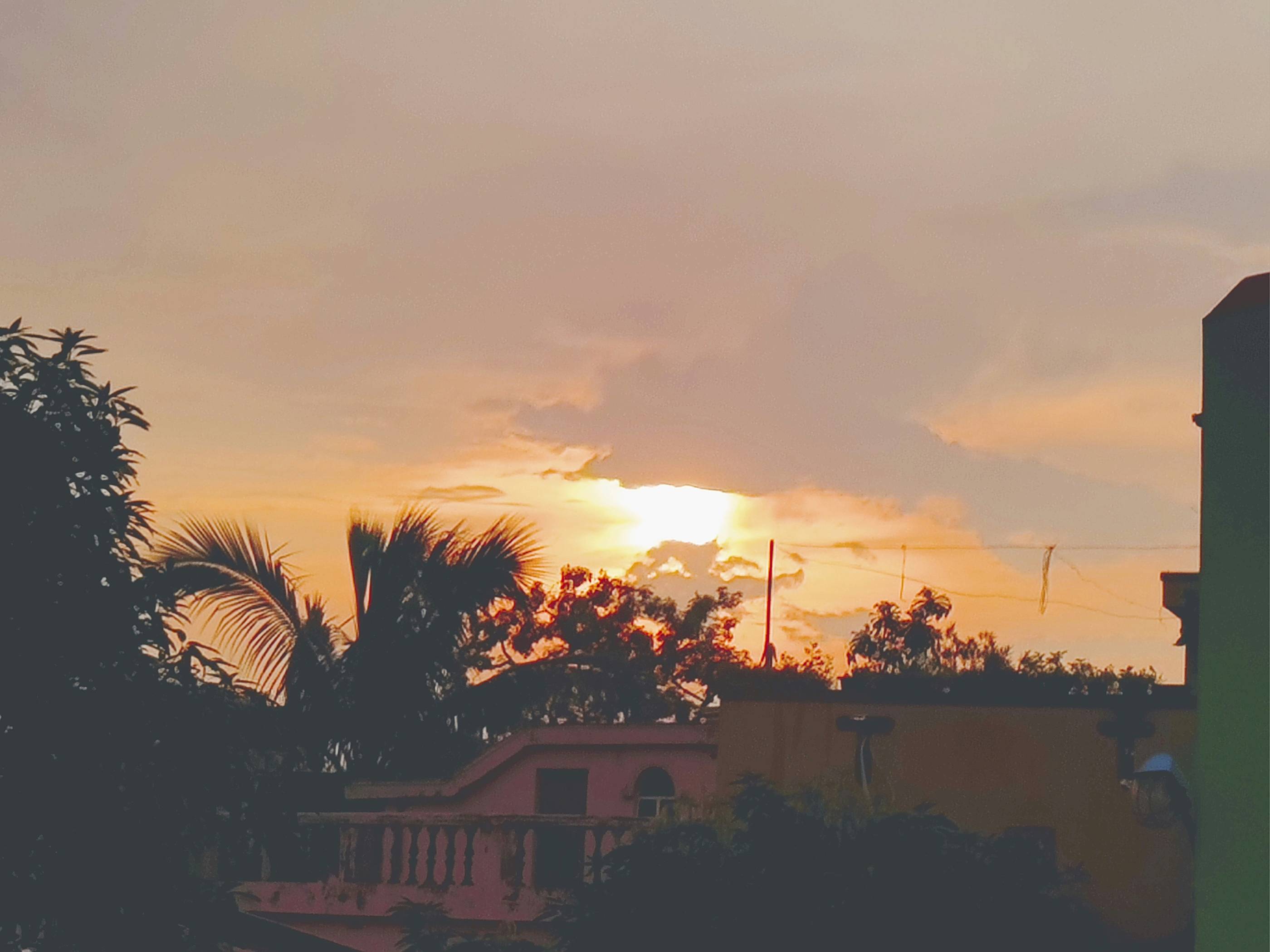 the sun is setting behind a building and trees