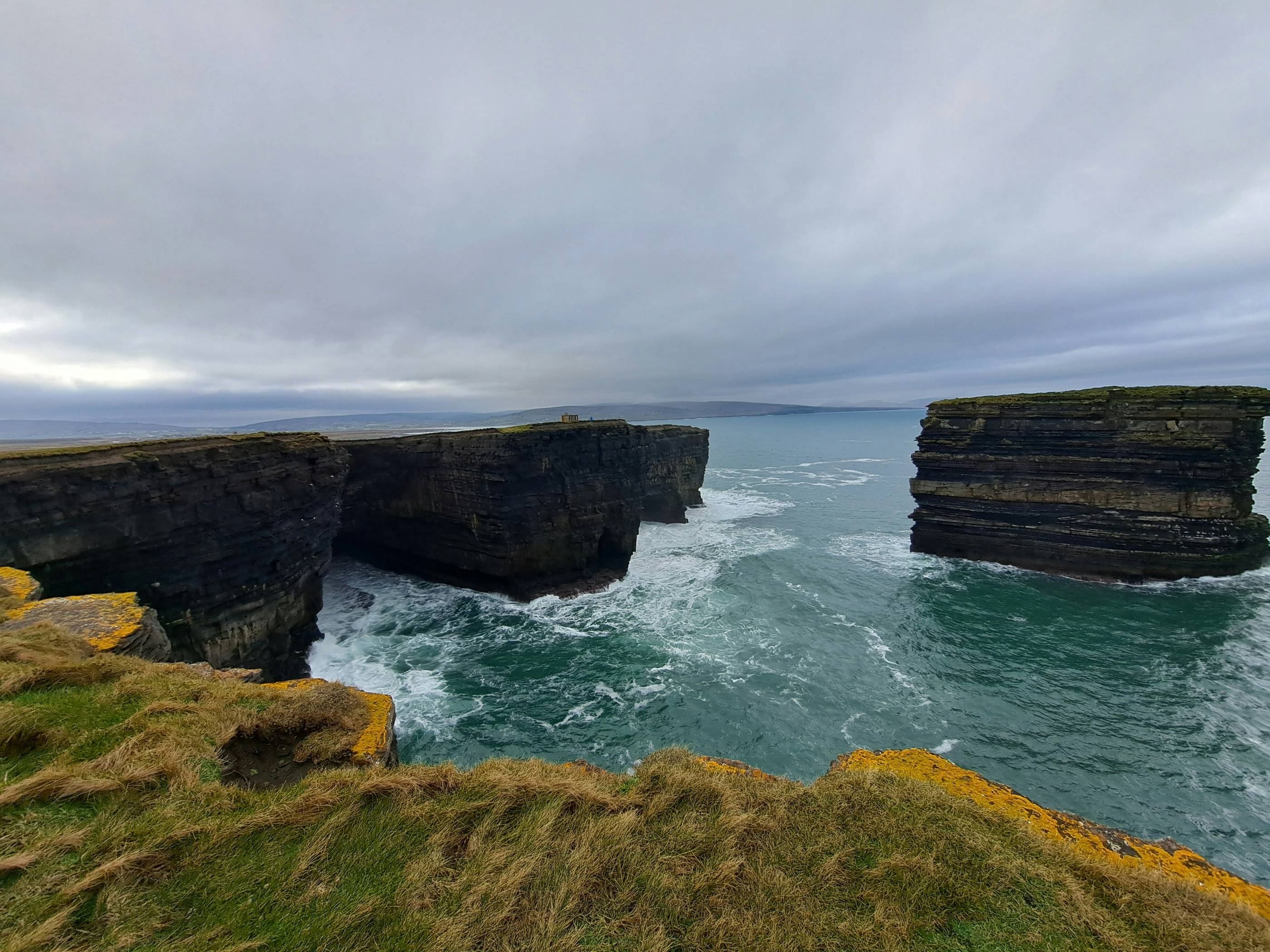Cliffs and ocean water beneath a cloudy sky.