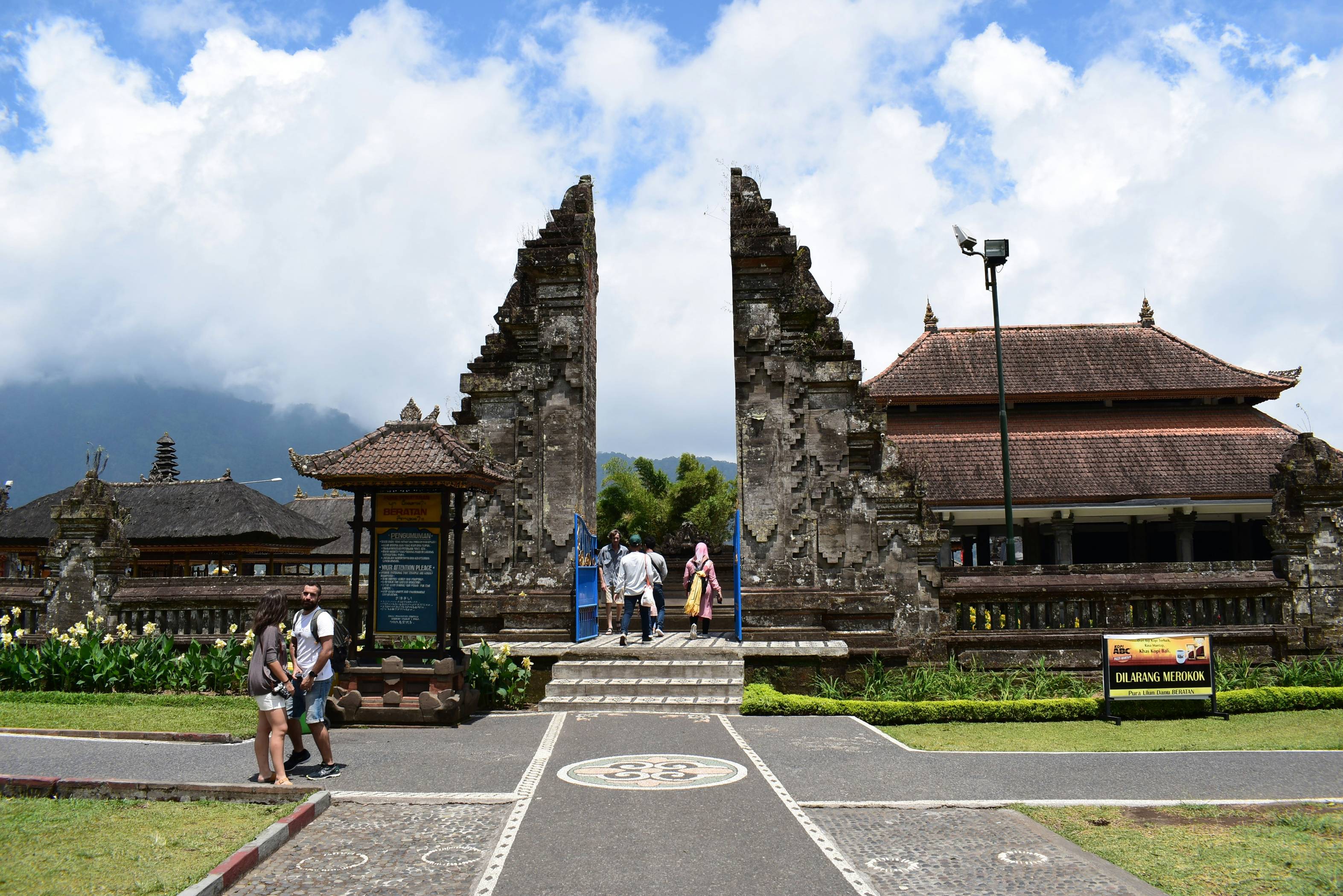 a group of people walking on a road next to a stone building